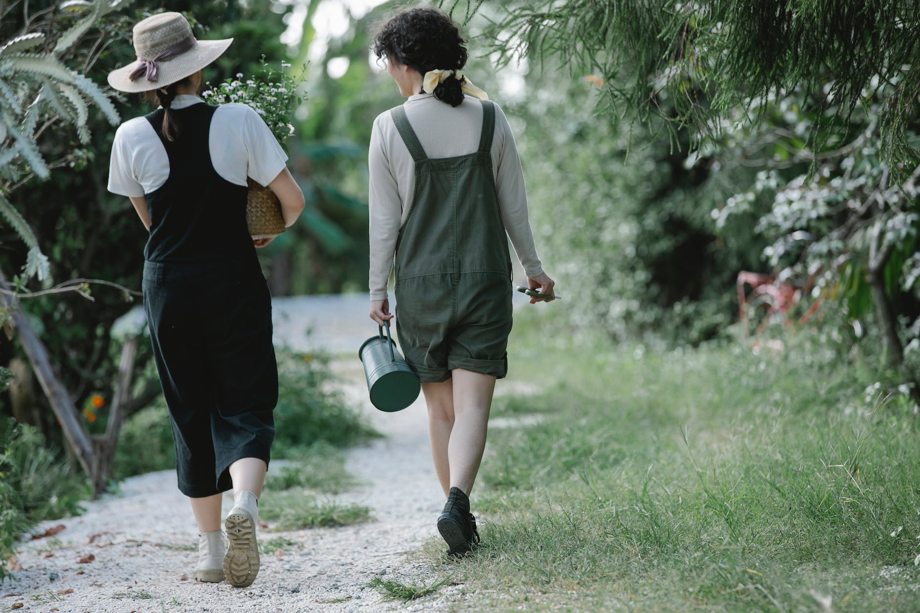 female gardeners carrying basket with flowers and watering can